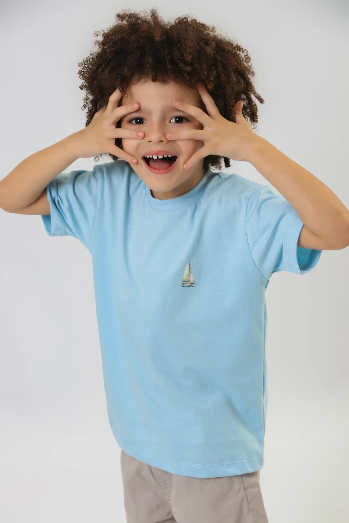 Camiseta azul com veleiro e um sorriso de brincadeira