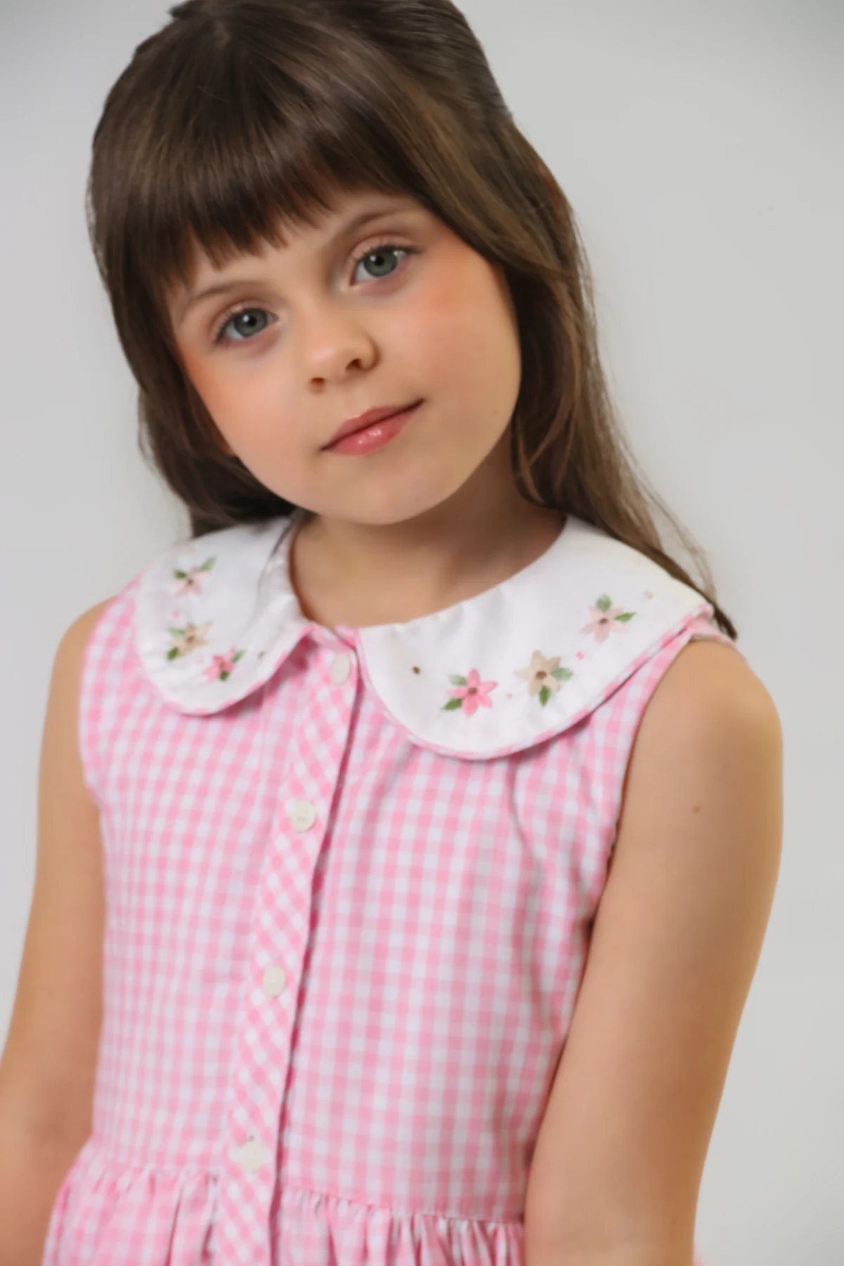Vestido xadrez rosa com gola bordada, em retrato da coleção Valutin